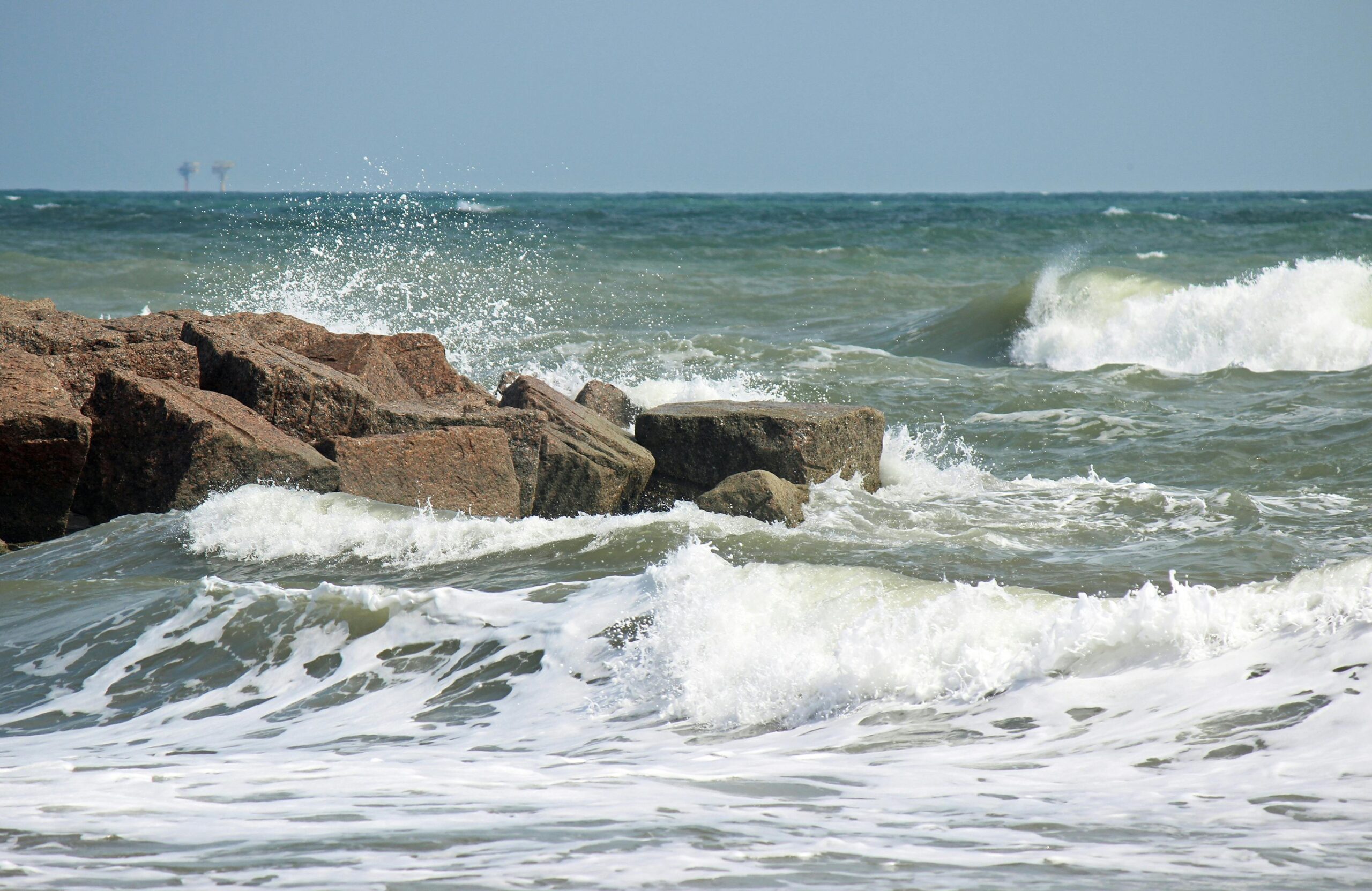 Dramatic waves crashing over rocks in Port Aransas, TX, capturing the raw power of the sea.