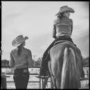 Women in cowboy hats enjoying a serene moment, one seated on a horse. Women in cowboy hats enjoying a serene moment, one seated on a horse.
